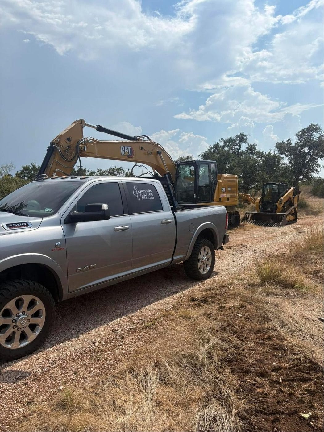 CAT excavator and track loader behind a JSC Earthworks truck on a Hill Country job