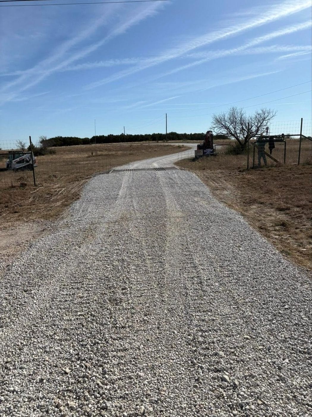 New gravel drive with a cattle guard at a ranch gate