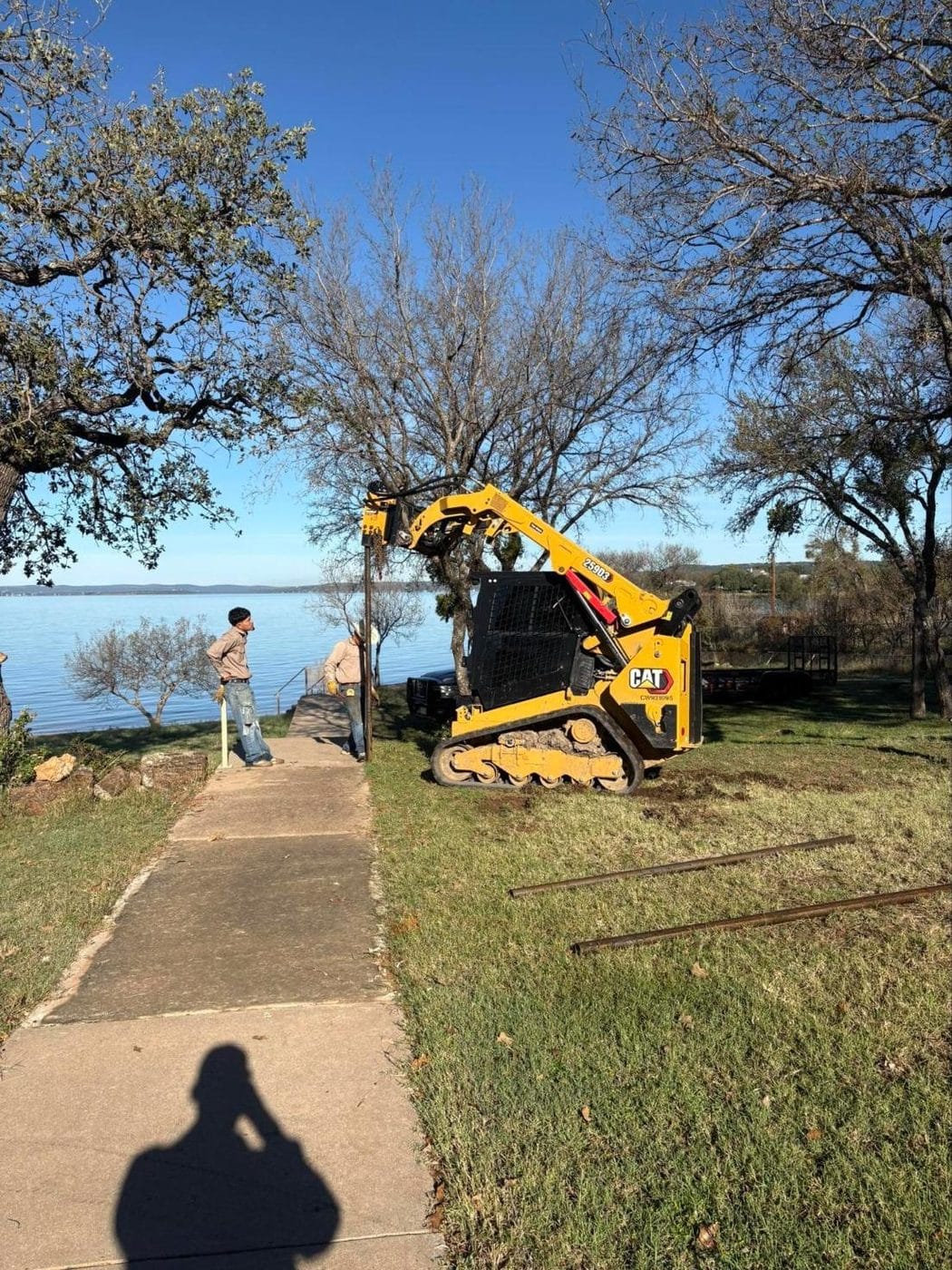 Track loader with an auger setting fence posts at a lakeside property